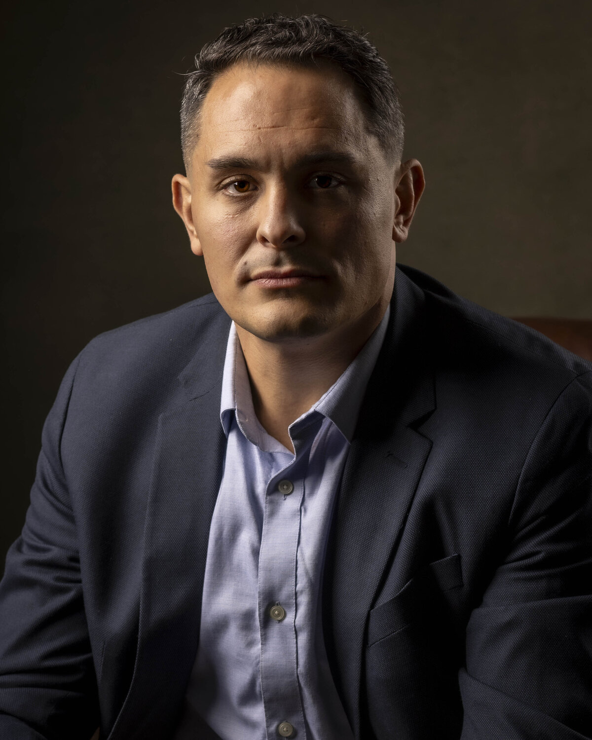 Headshot in MA of bald man in navy jacket and light shirt, smiling against warm background by Rob Faber Photography.