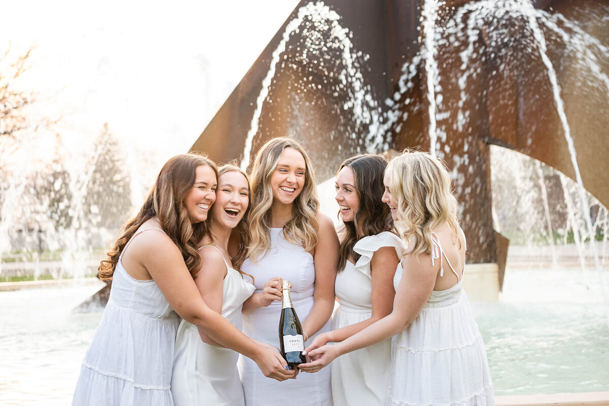 Friends showcasing their bottle of champagne shortly before opening to celebrate their graduation from MSU, Mankato.