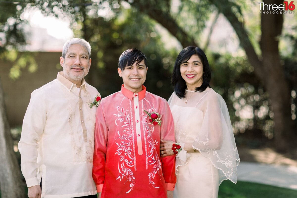 Groom poses with his parents before the ceremony