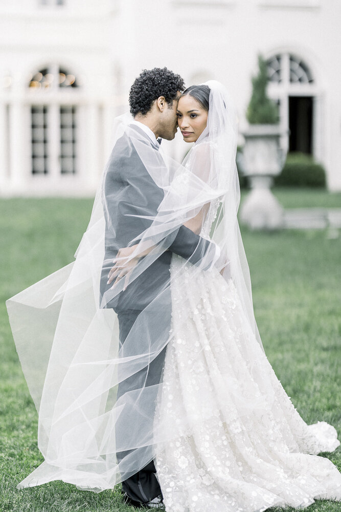 a bride and groom embracing while surrounded by wedding veil
