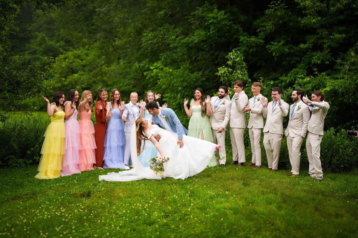 Bride and groom sharing a joyful moment with their bridal party in colorful dresses