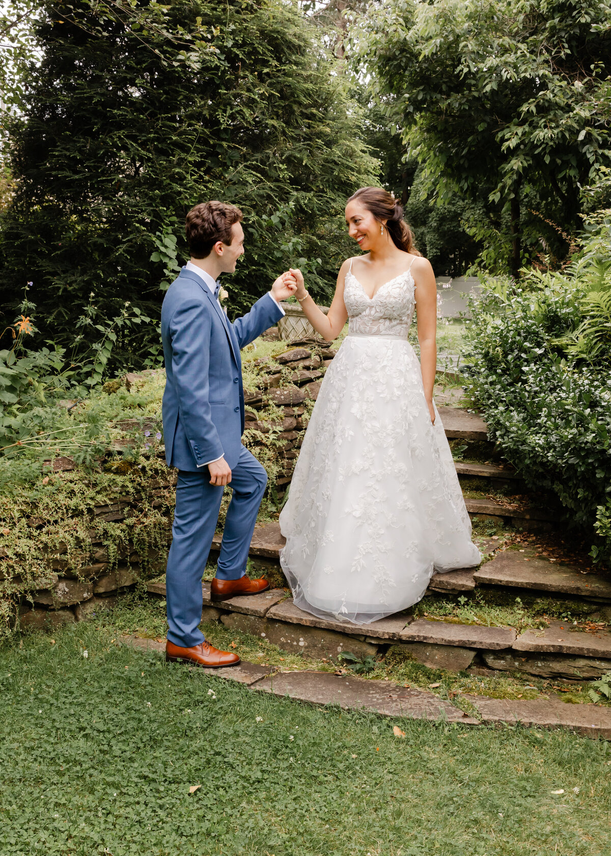 An intimate moment as the groom guides his bride down the stairs at The Lilac Inn in Brandon, Vermont, beautifully captured on their wedding day