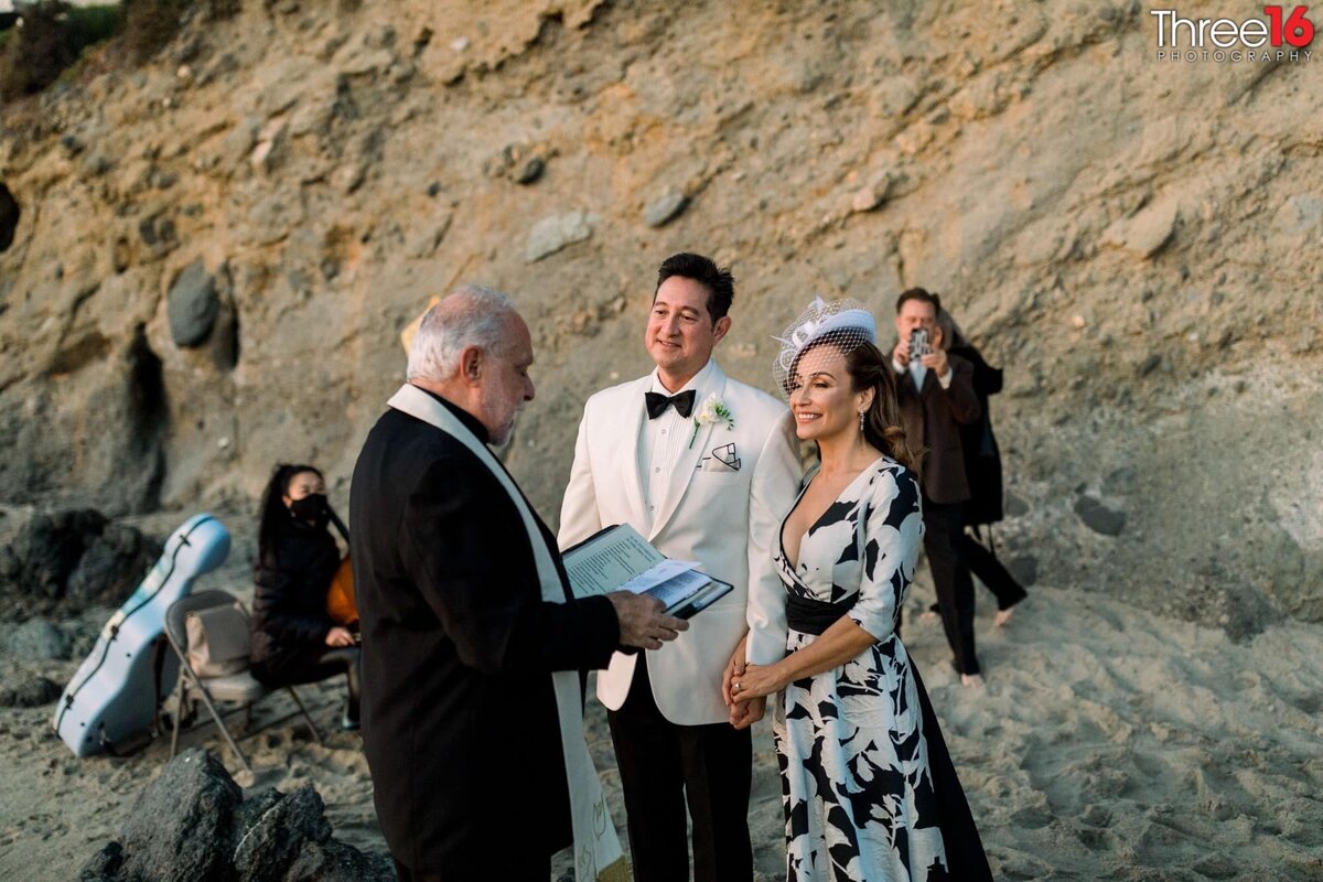 Bride and Groom face the officiant during a beach setting elopement ceremony