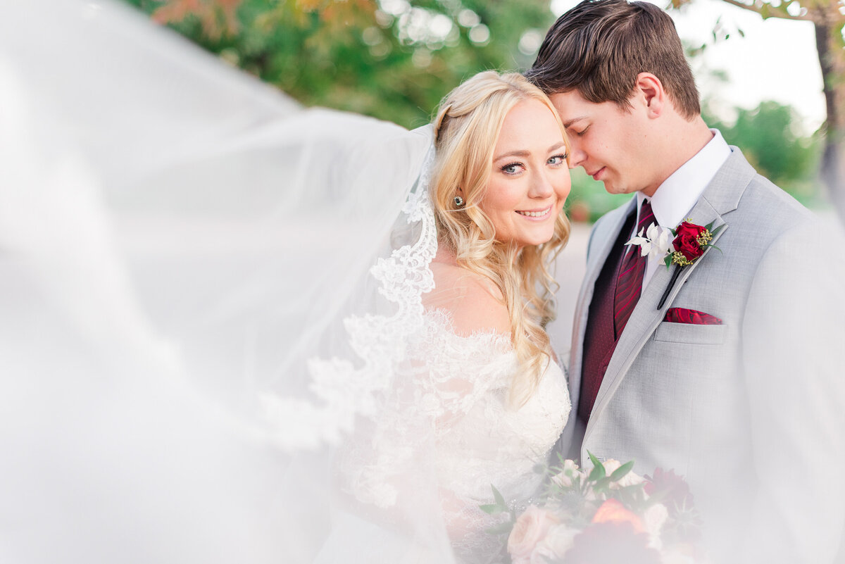 Artistic photo of a couple touching foreheads with the bride's veil sweeping in towards the camera.