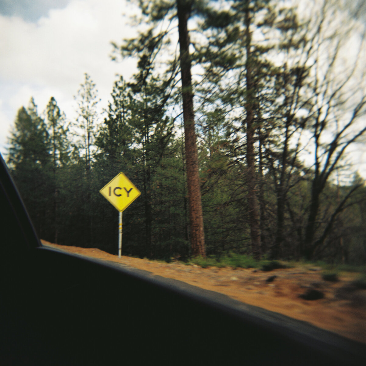 Motion blur of an icy sign captured on film with a Holga camera by Kate Winters Photography, showcasing a nostalgic and authentic moment in a documentary style.
