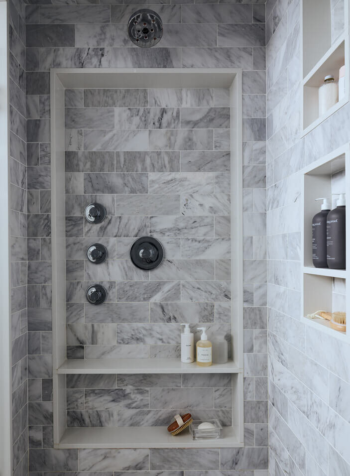 Hingham kitchen and bath designer creates a marble walk-in shower with Kohler fixtures, combining luxury with functionality for a timeless bathroom design.