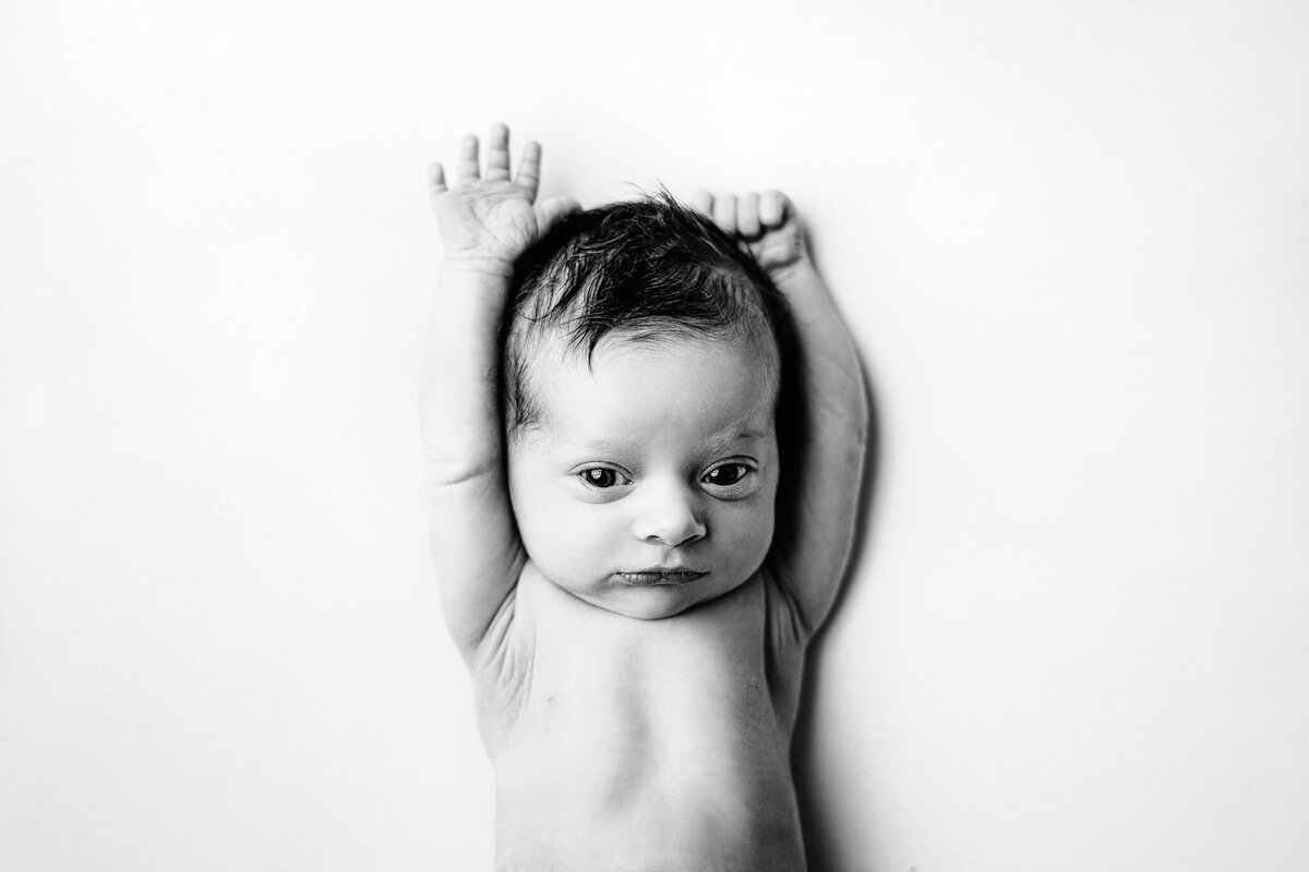 newborn baby personality portrait stretching and making a cute expression during baby photo shoot in traverse city mi
