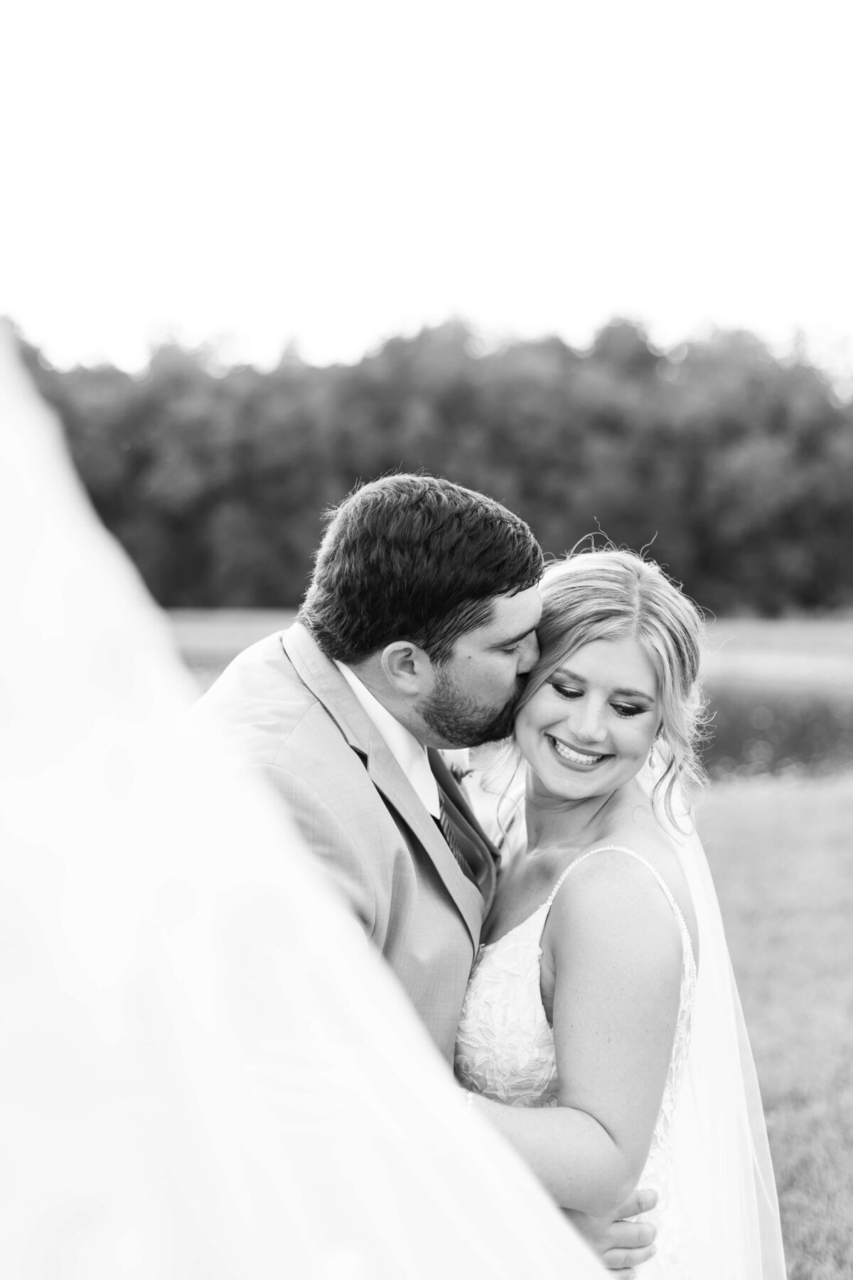 Groom kissing bride on the cheek at  The Barn at White Oaks, Murray, Kentucky