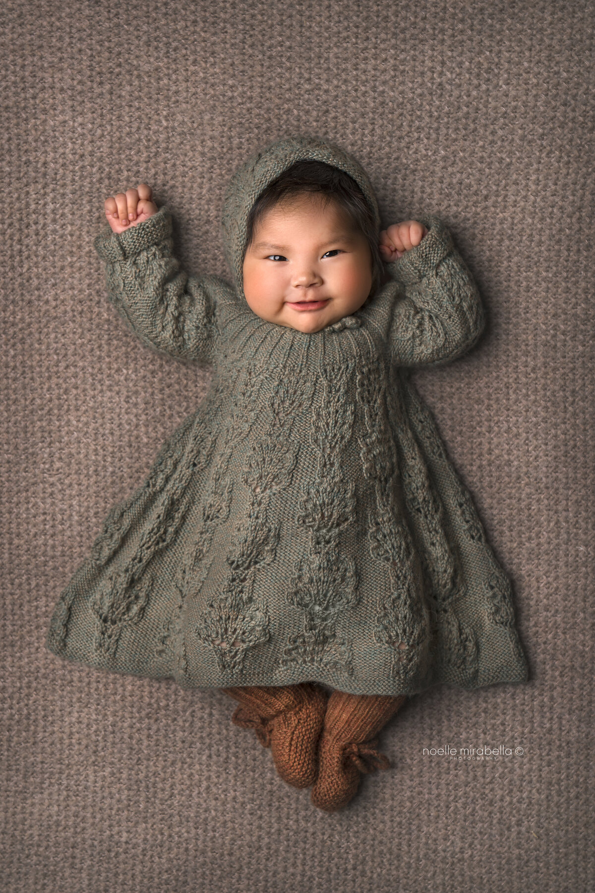 Baby in a sage knit dress and rust knit booties.