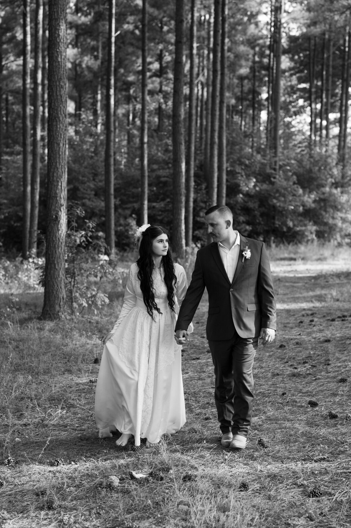 A wedding couple holding hands and walking in a wooded area