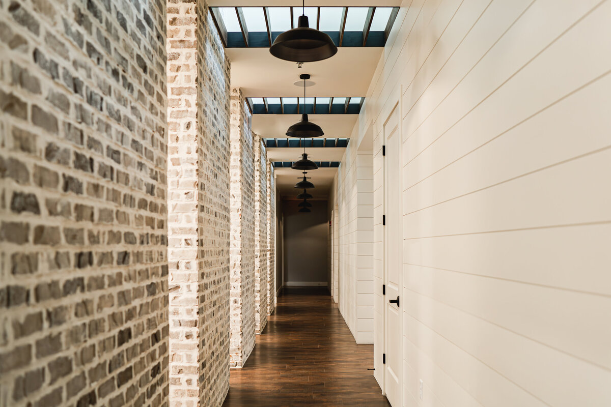 building hallway with barn pendant lights, skylights, brick wall and shiplap
