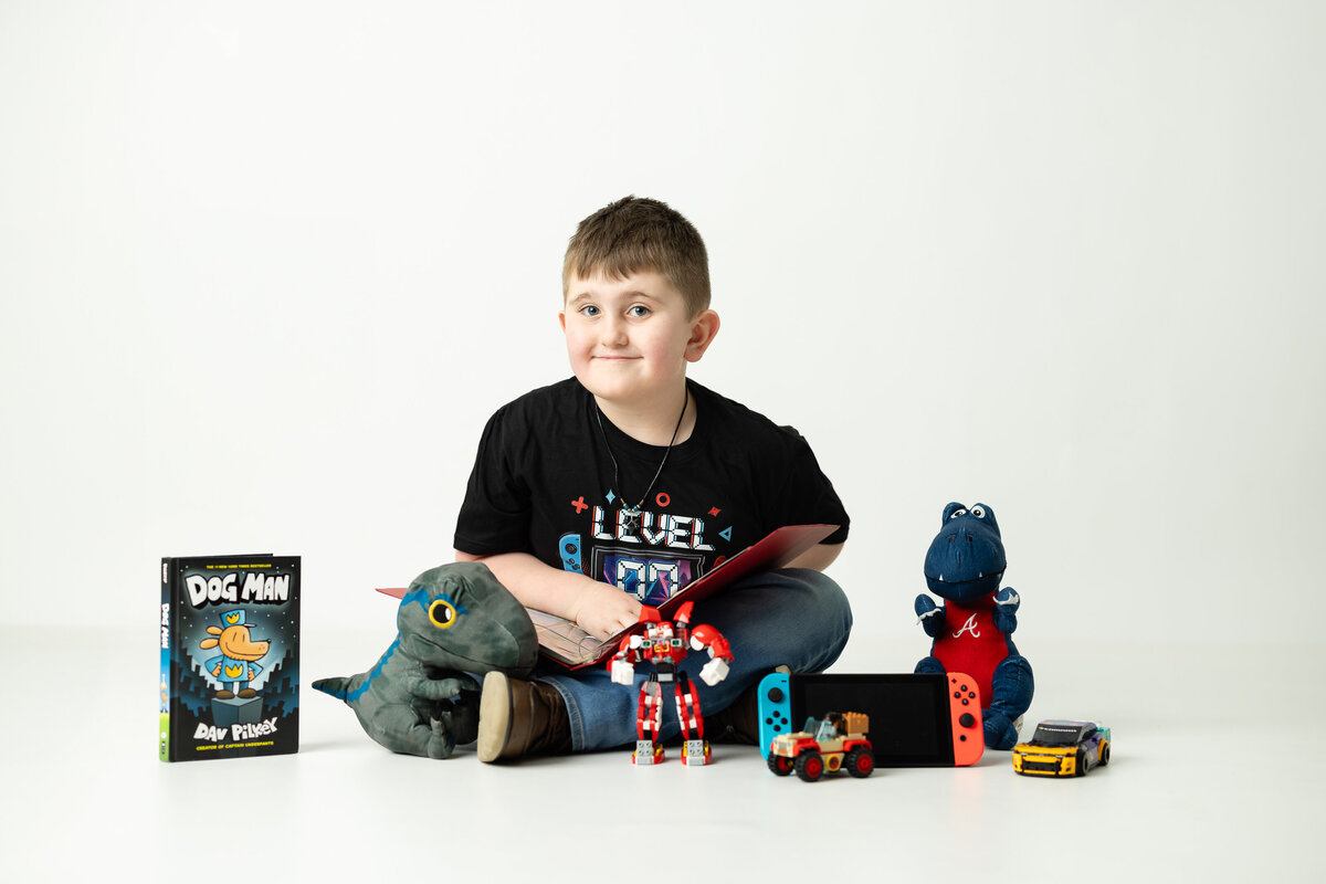 Boy playing with action figure toys in a themed birthday session, full of energy and excitement, photographed by Victoria Lee Photography in Canton, GA