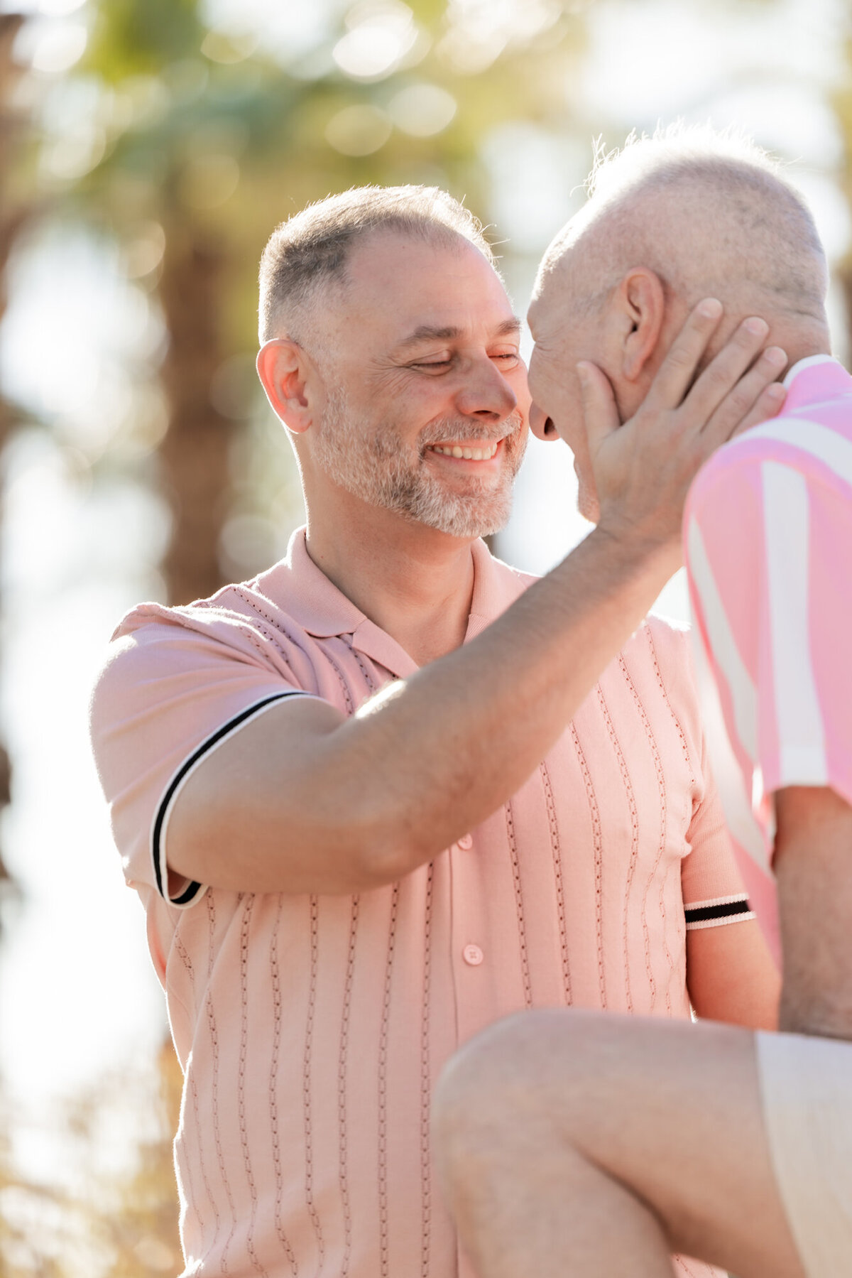 Close-up of couple hugging with joy and laughter, framed by soft sun and natural desert tones.