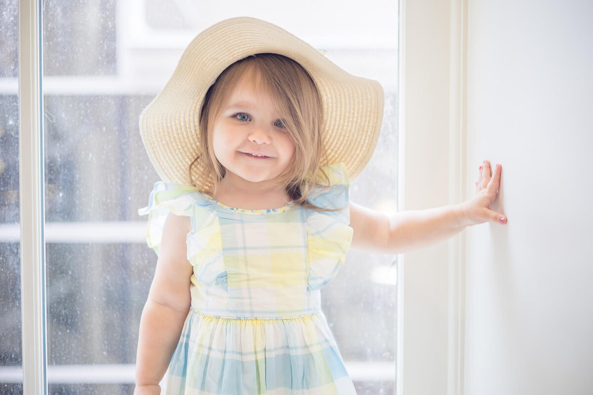 Happy toddler girl in a sunhat and blue and yellow dress