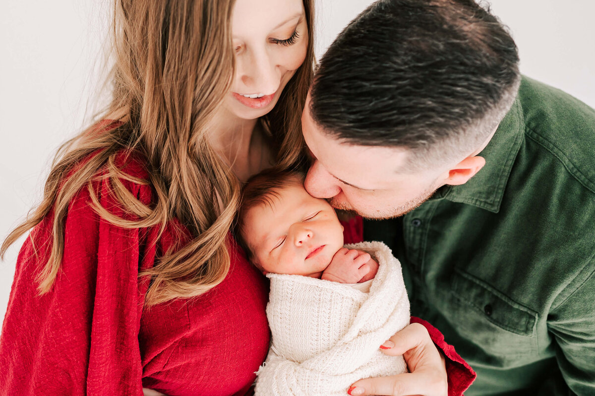 Springfield Mo newborn photographer Jessica Kennedy of The XO Photography cpatures dad kissing newborn in moms arms