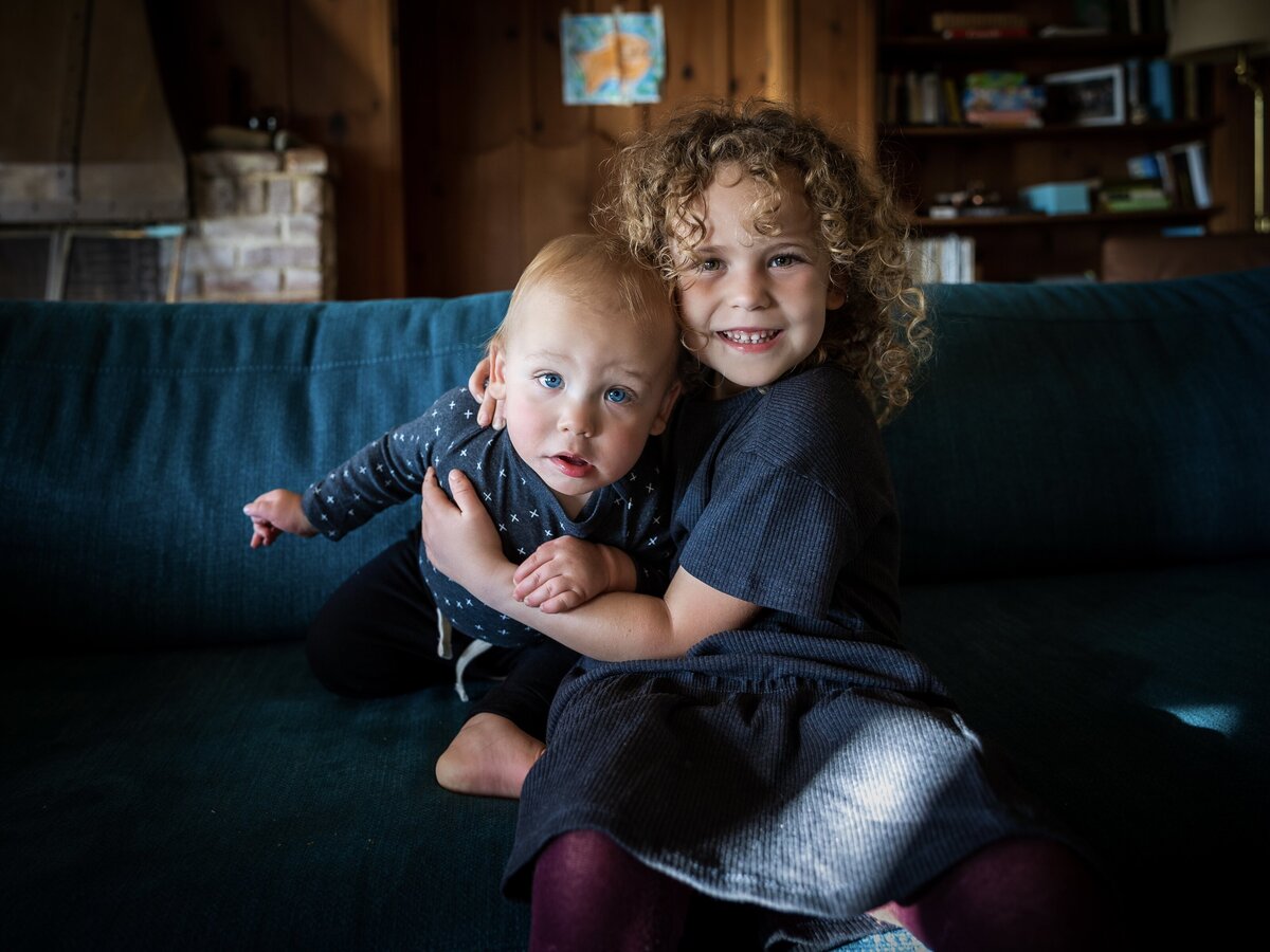 Sister holds brother on the couch
