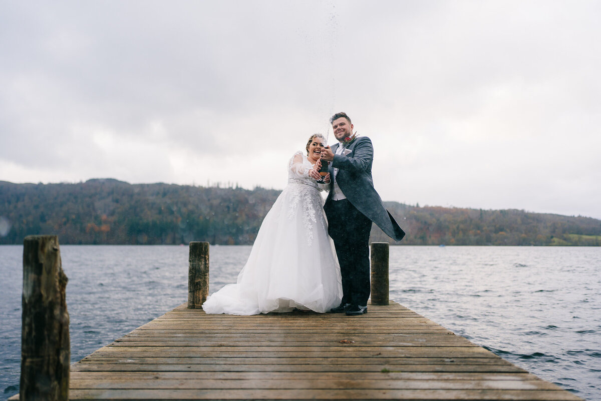 bride and groom spraying champagne at Miller Ground on lake windermere inthe lake district taken  by wedding photographer Anthony Horseman