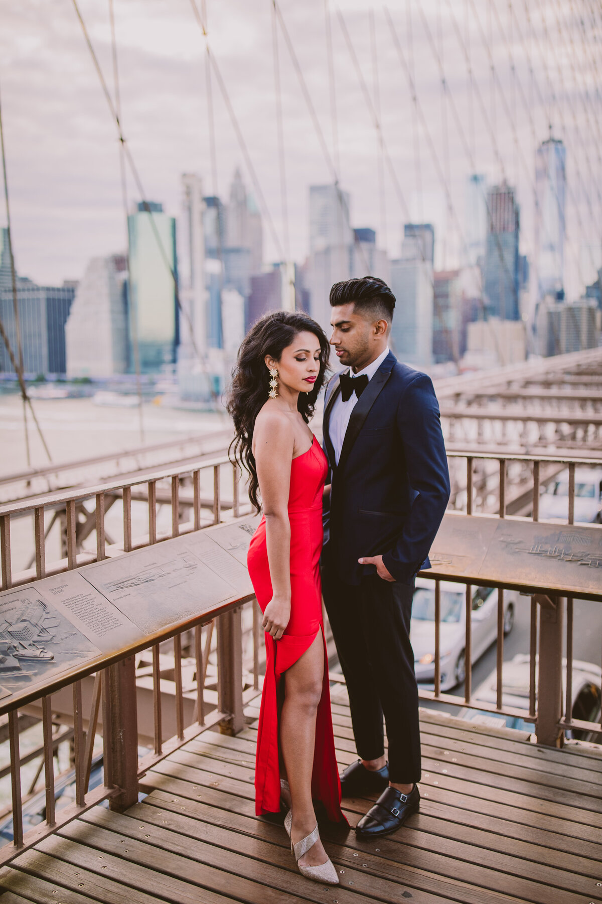 A couple in red outfits standing on the brooklyn bridge in dumbo in nyc
