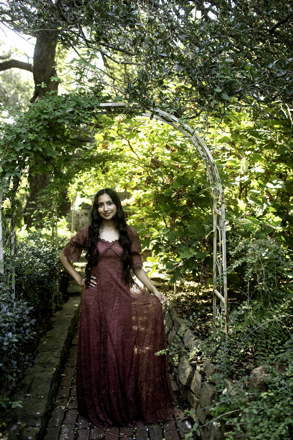A senior in a beautiful dress, standing against the stunning backdrop of Chandor Gardens' floral arches, symbolizing new beginnings and unforgettable memories