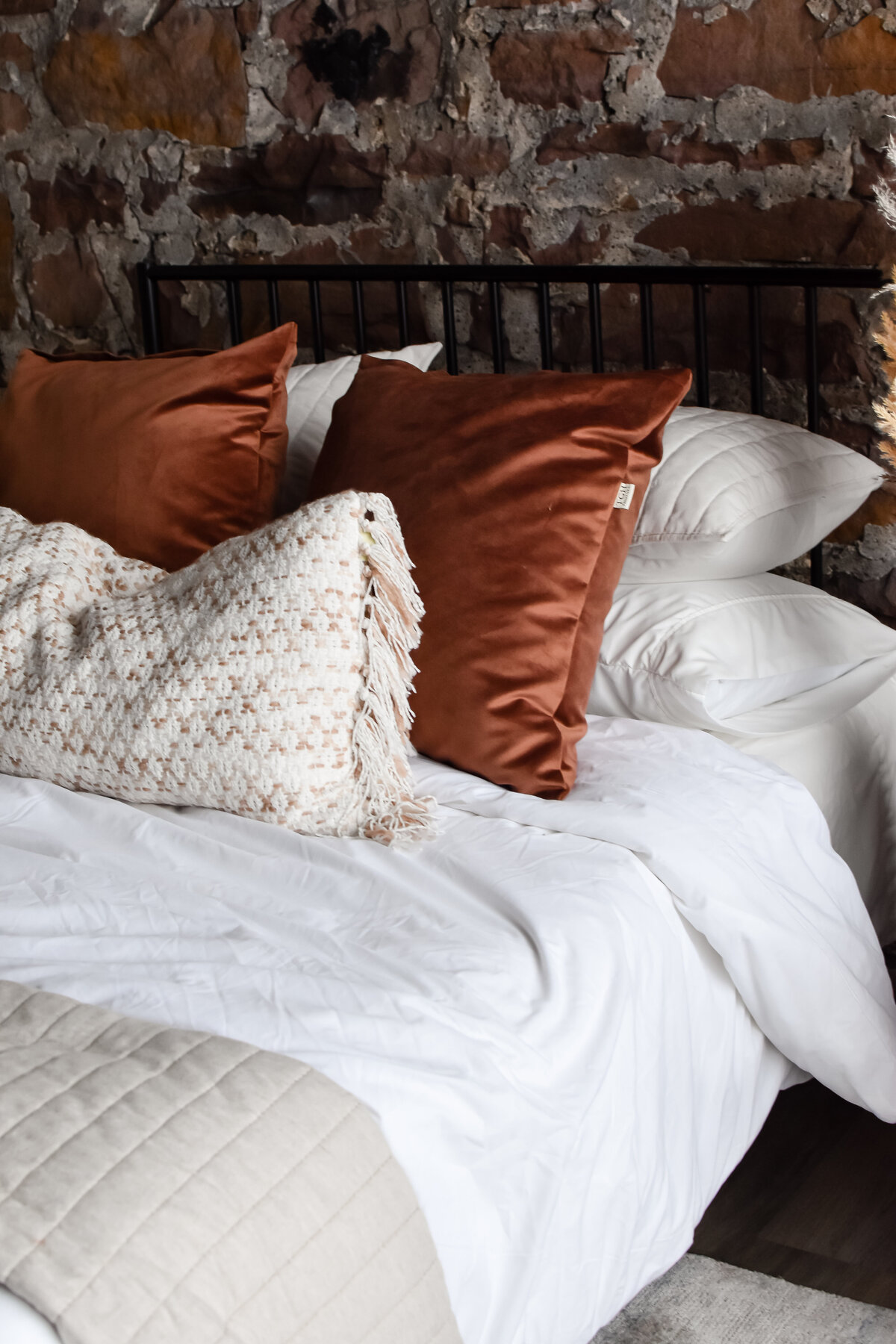 Two orange velvet pillows sit on a plush bed