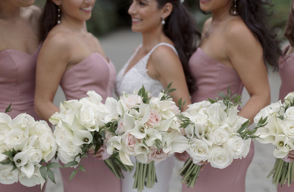 Bridesmaids pose in pink silk dresses and white lily bouquets during wedding at the Chanler Newport.