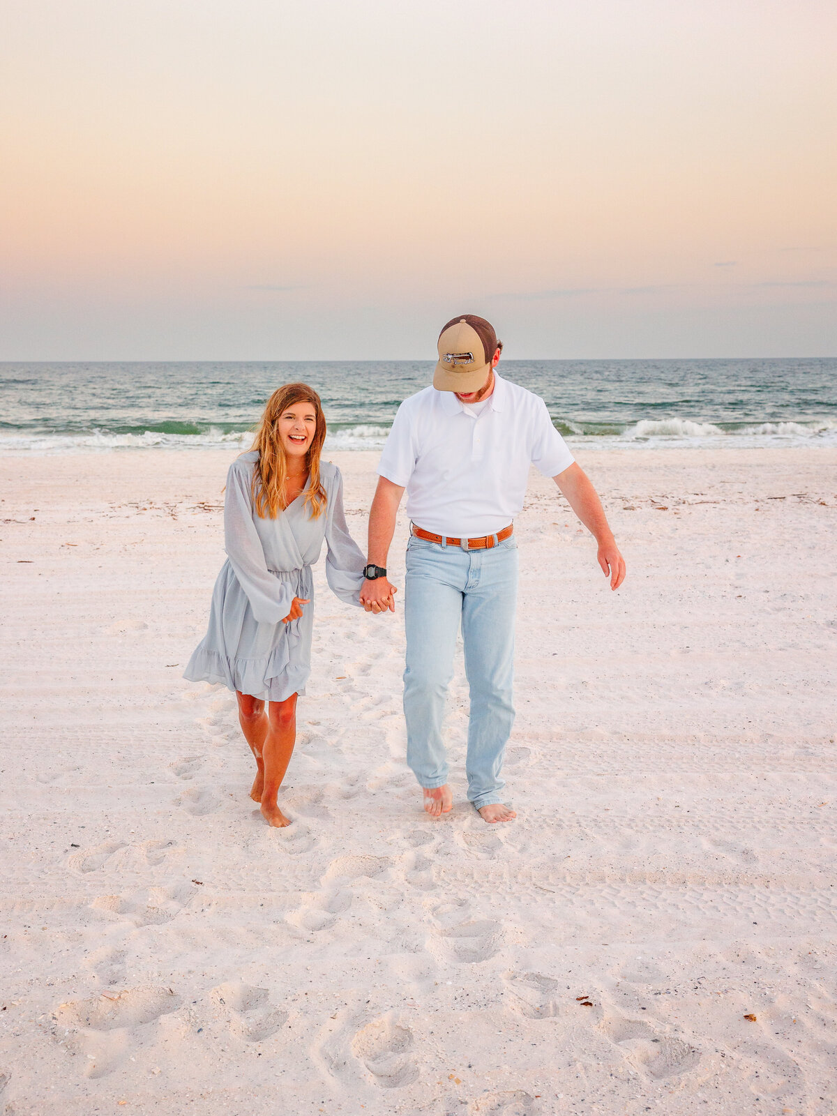 Authentic joy as a couple stumbles and laughs while walking hand in hand on the beach
