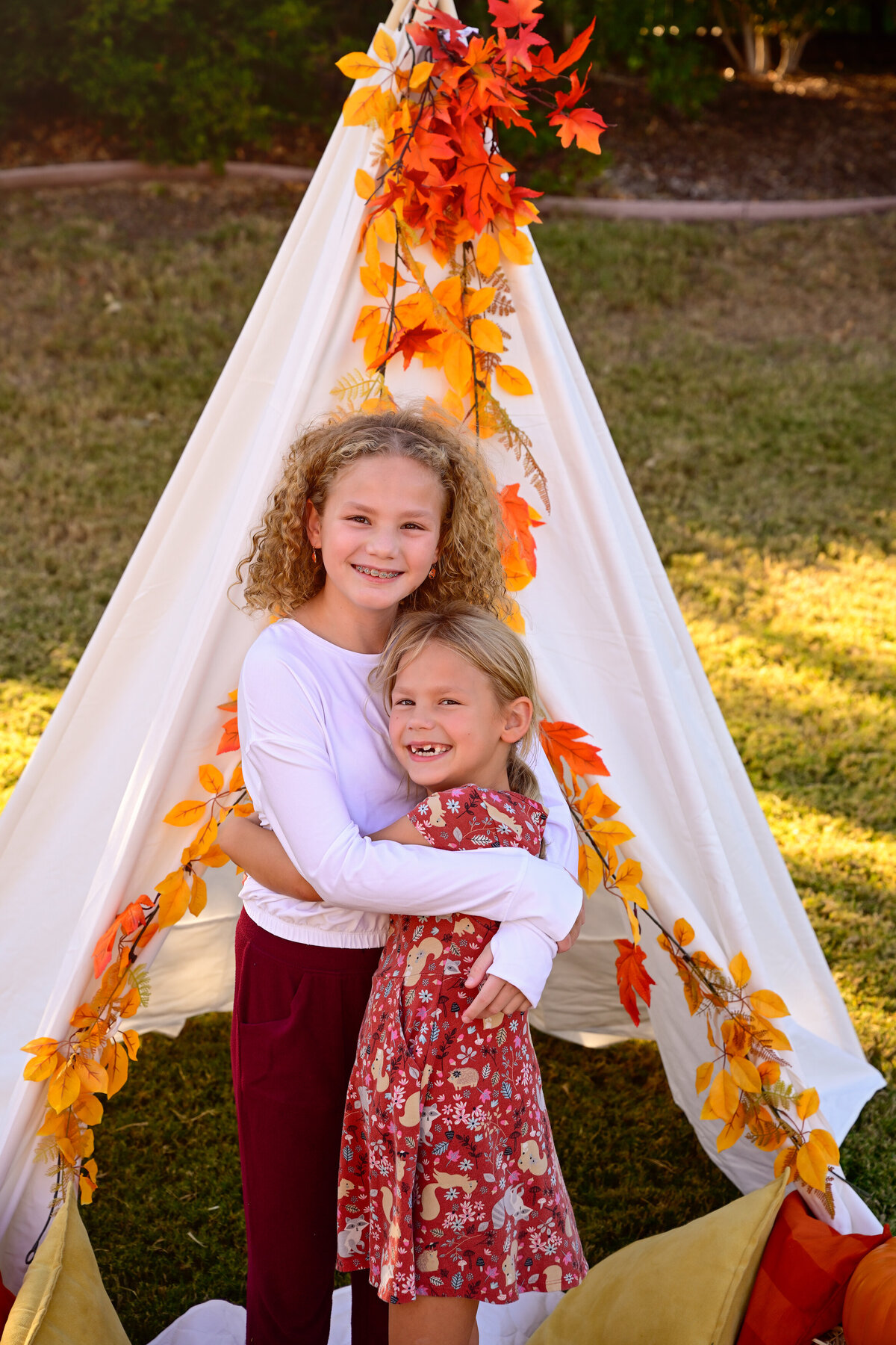 Two sisters hug each other while playing in their tent during their McKinney, TX outdoor family photo session.