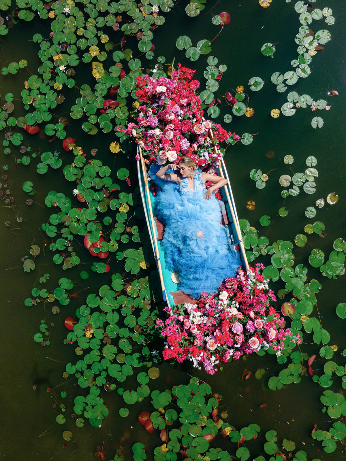Couple laying down in a small boat on the lake with pink florals