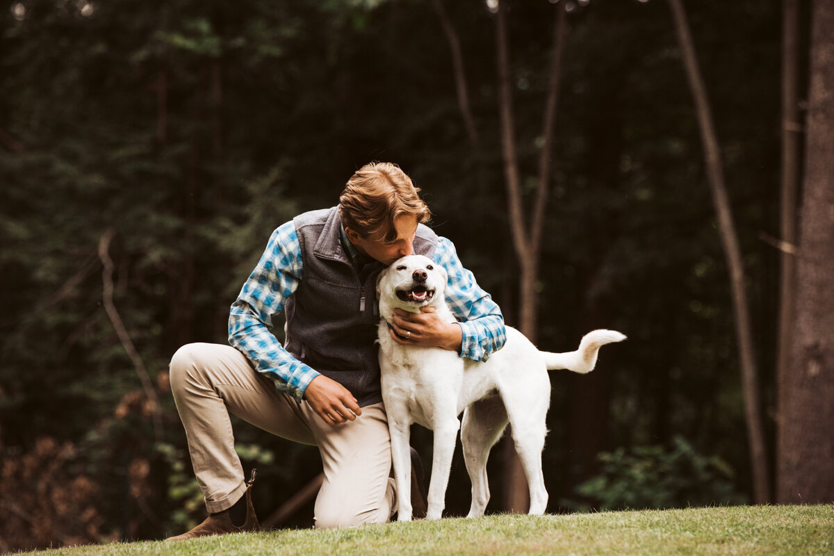 A teenage boy kneeling to hug his dog Vermont Senior Portraits