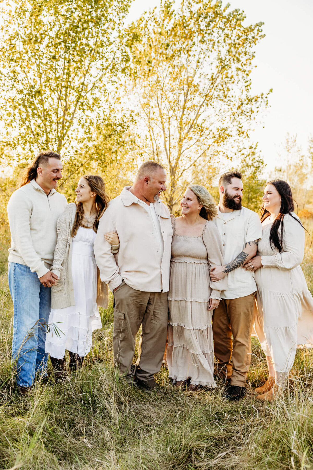 beautiful family  standing and embracing one another as they look at each other and laugh during their family photo session.