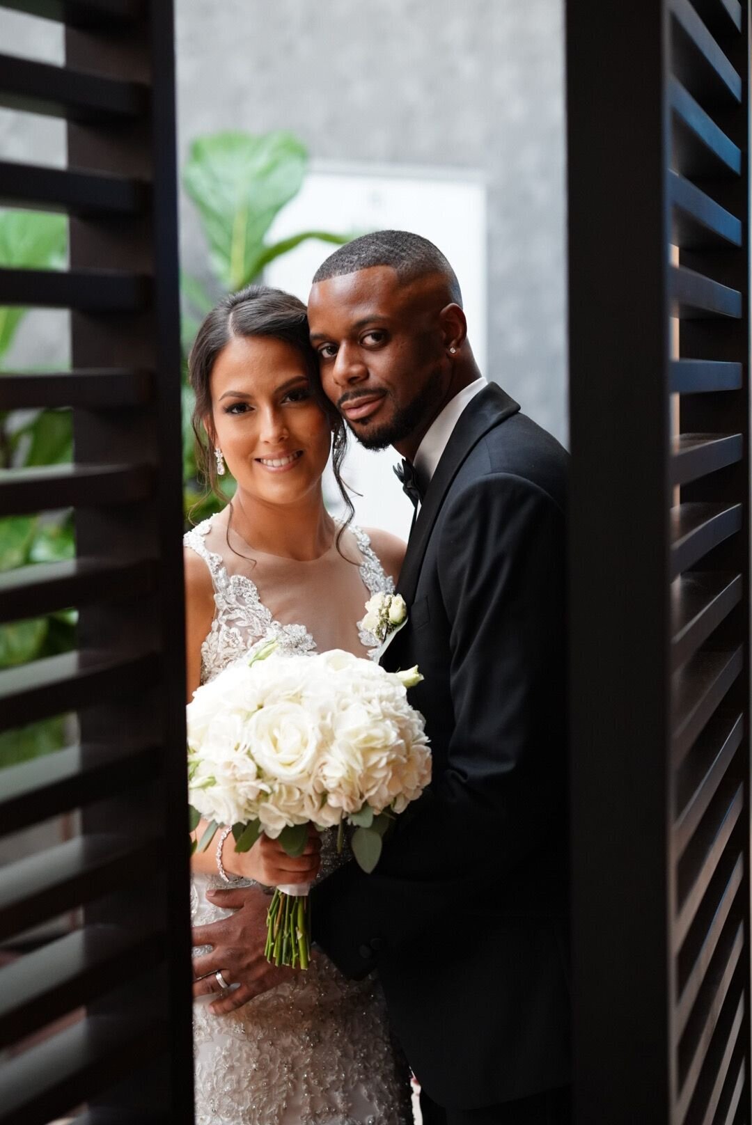 A creative shot capturing the wedding couple through the frame of an open door, offering a glimpse into their private moment. This unique perspective adds depth and intimacy to the image, highlighting the connection between the bride and groom as they share a special moment away from the crowd.