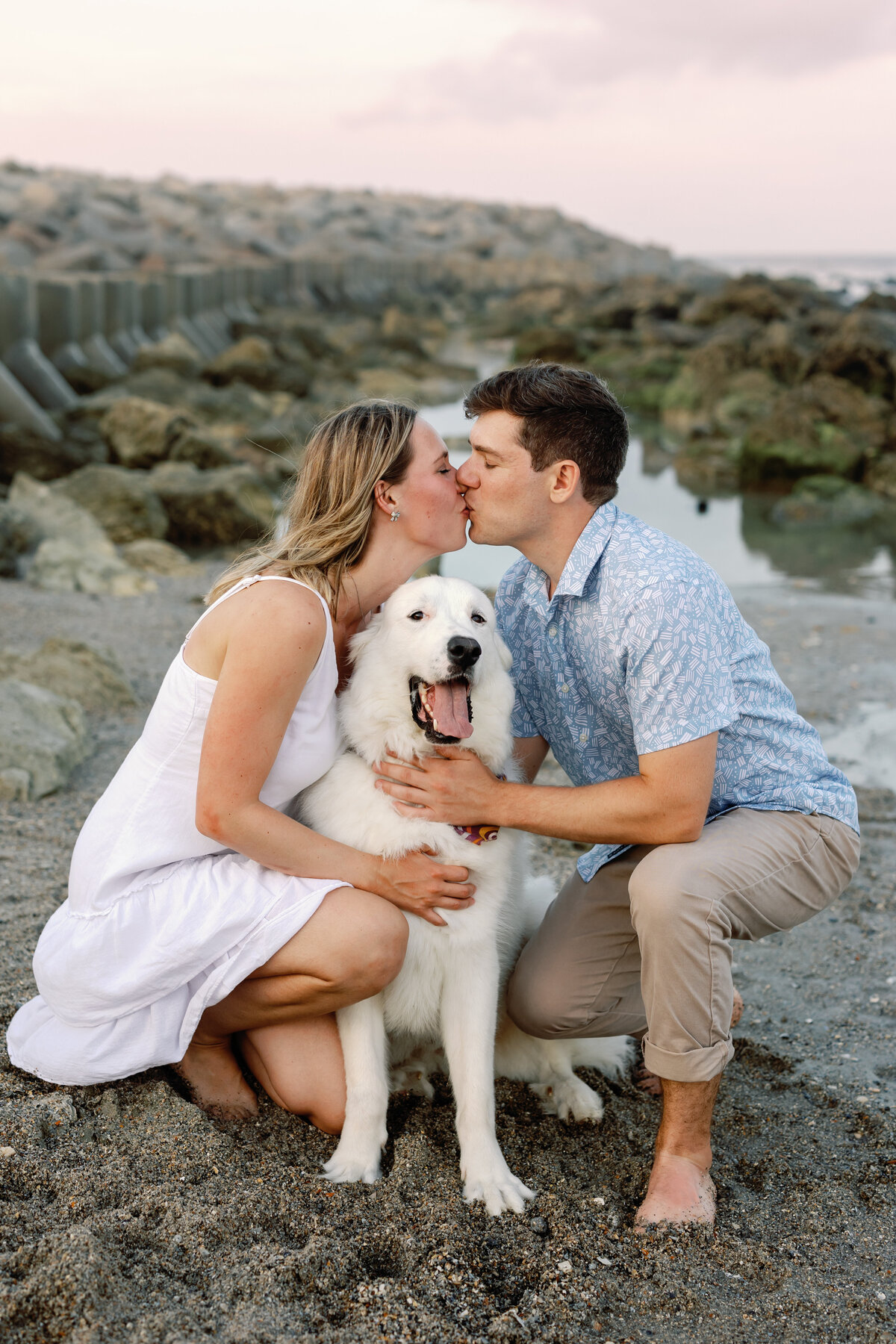 Couple kissing with their dog between them, playful Wilmington beach engagement photo