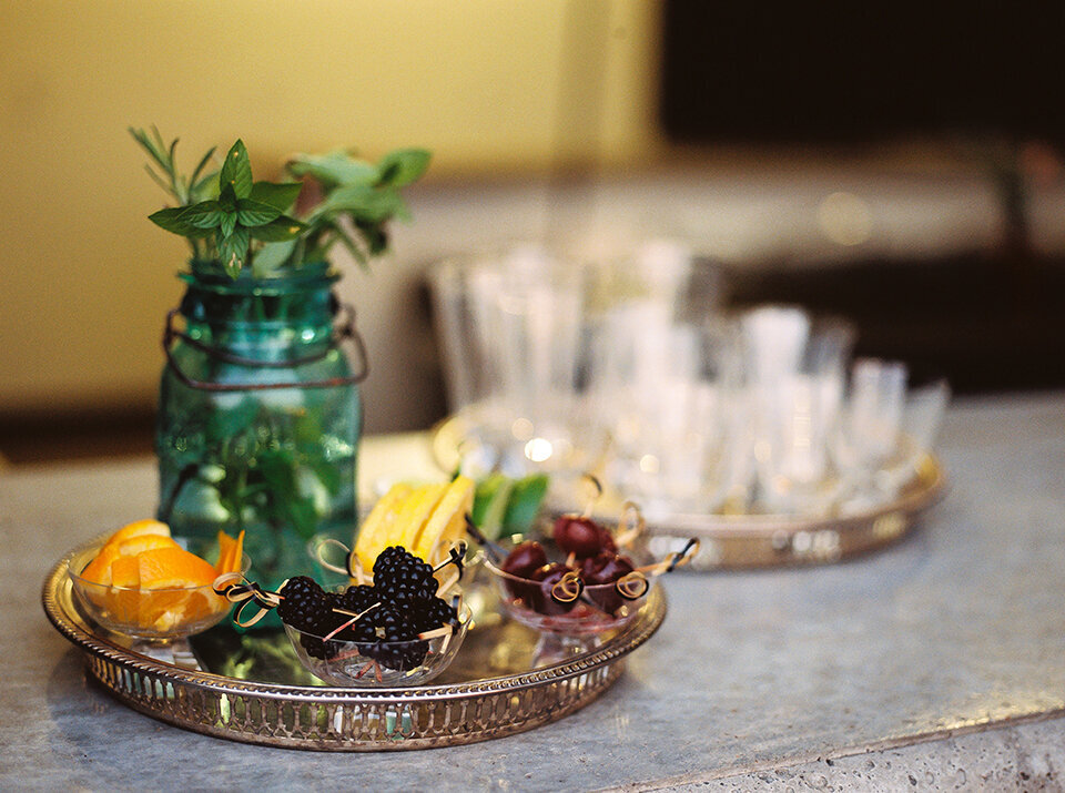 Fruit cocktail toppings on glass bowls set on a gold tray, with mint in a green mason jar.