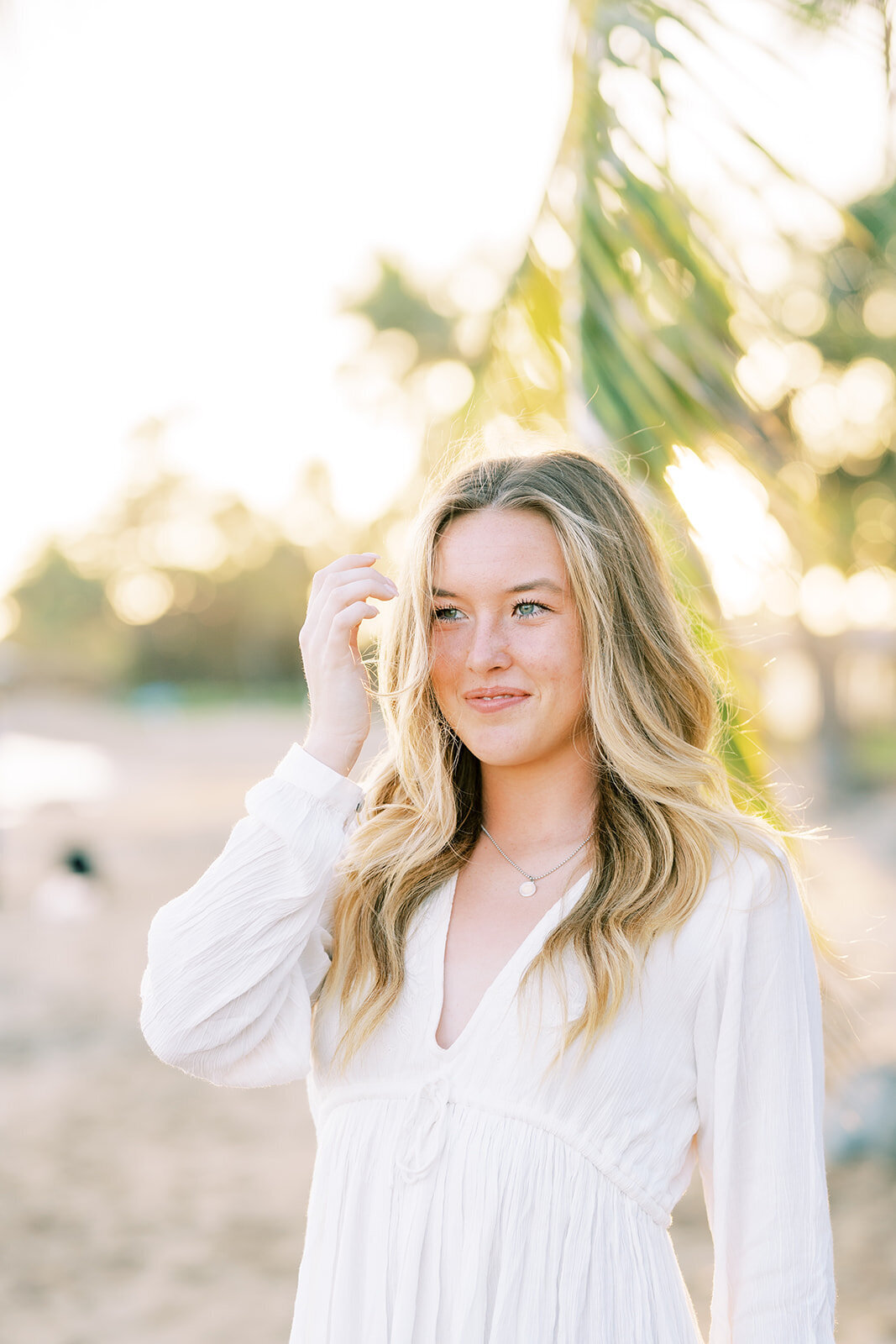 girl in a white shirt brushes hair out of face