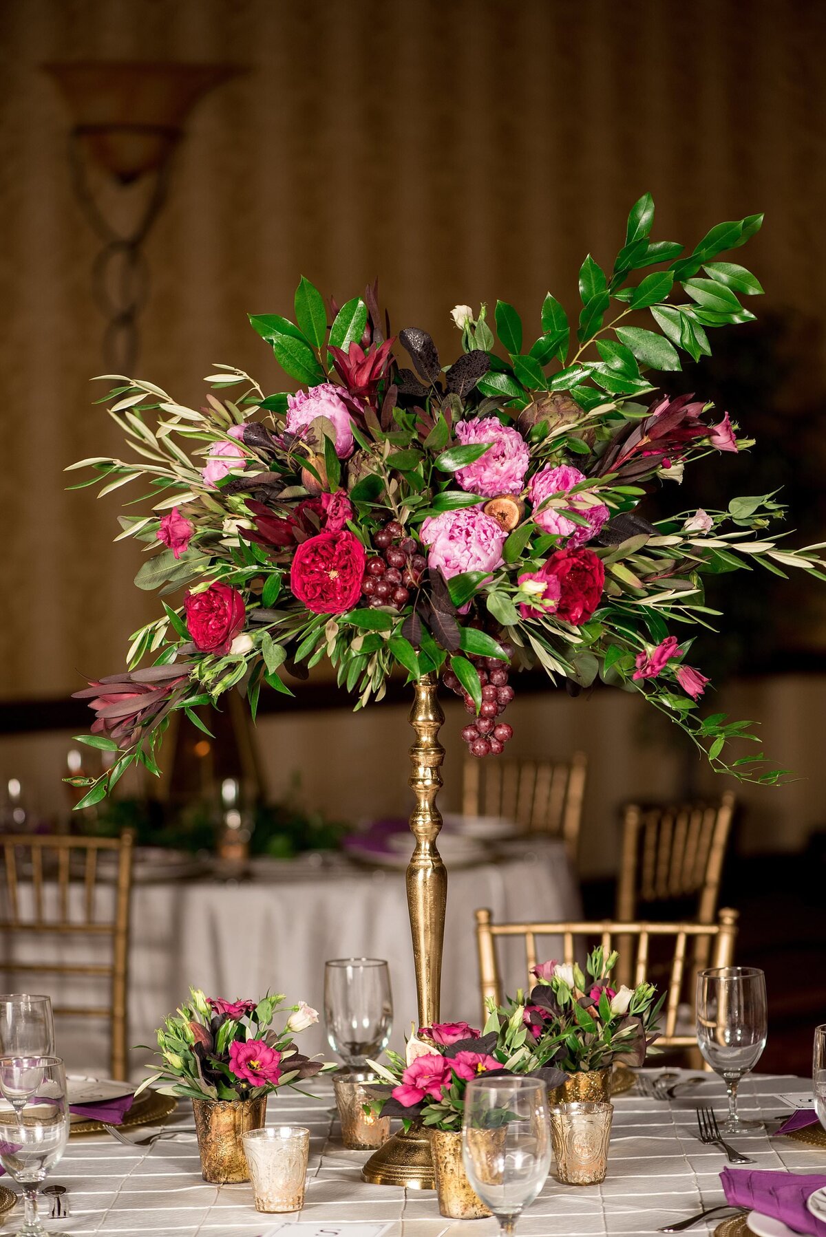 wedding centerpiece with fruit, pink and magenta flowers and gold candles