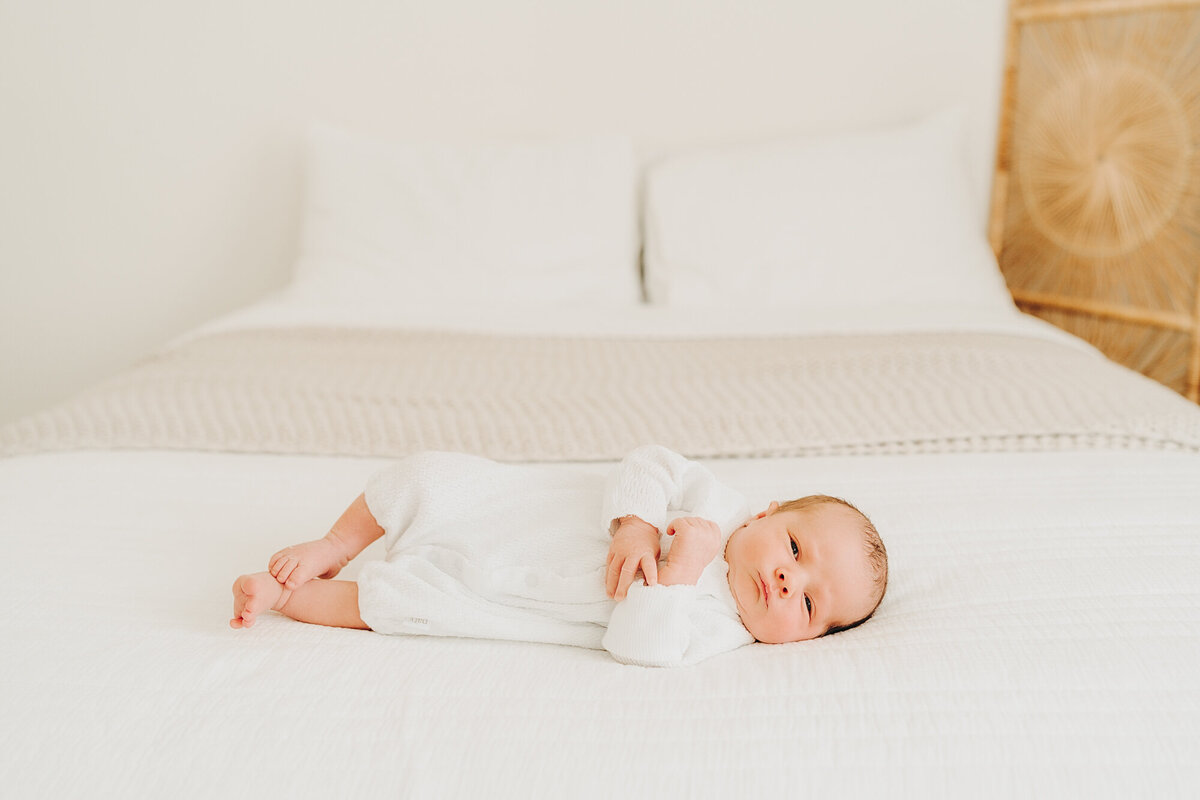 baby looking at camera while laid on bed at his newborn session in jackson missouri