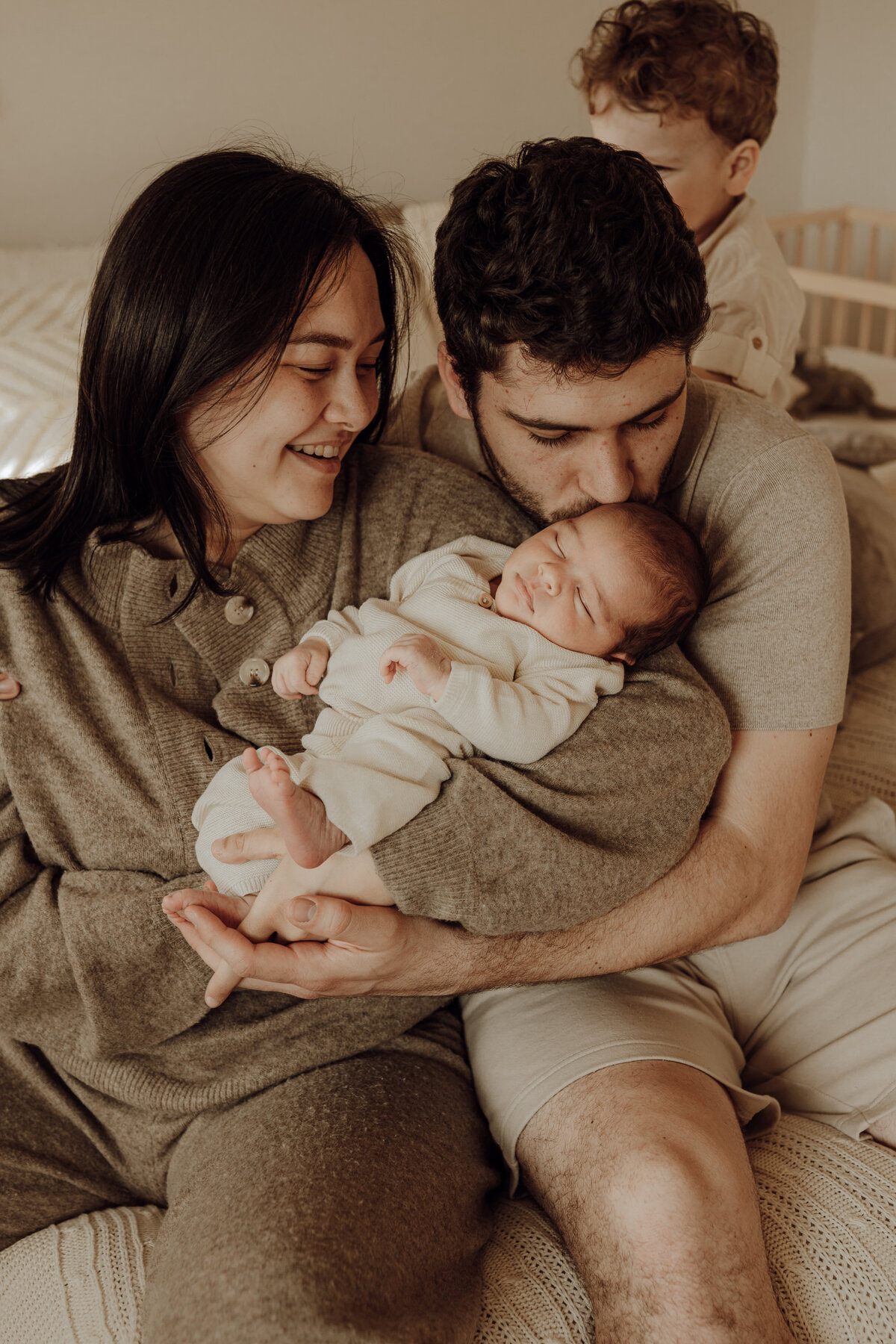 Koppel kijkt liefdevol naar hun slapende baby tijdens newborn fotoshoot