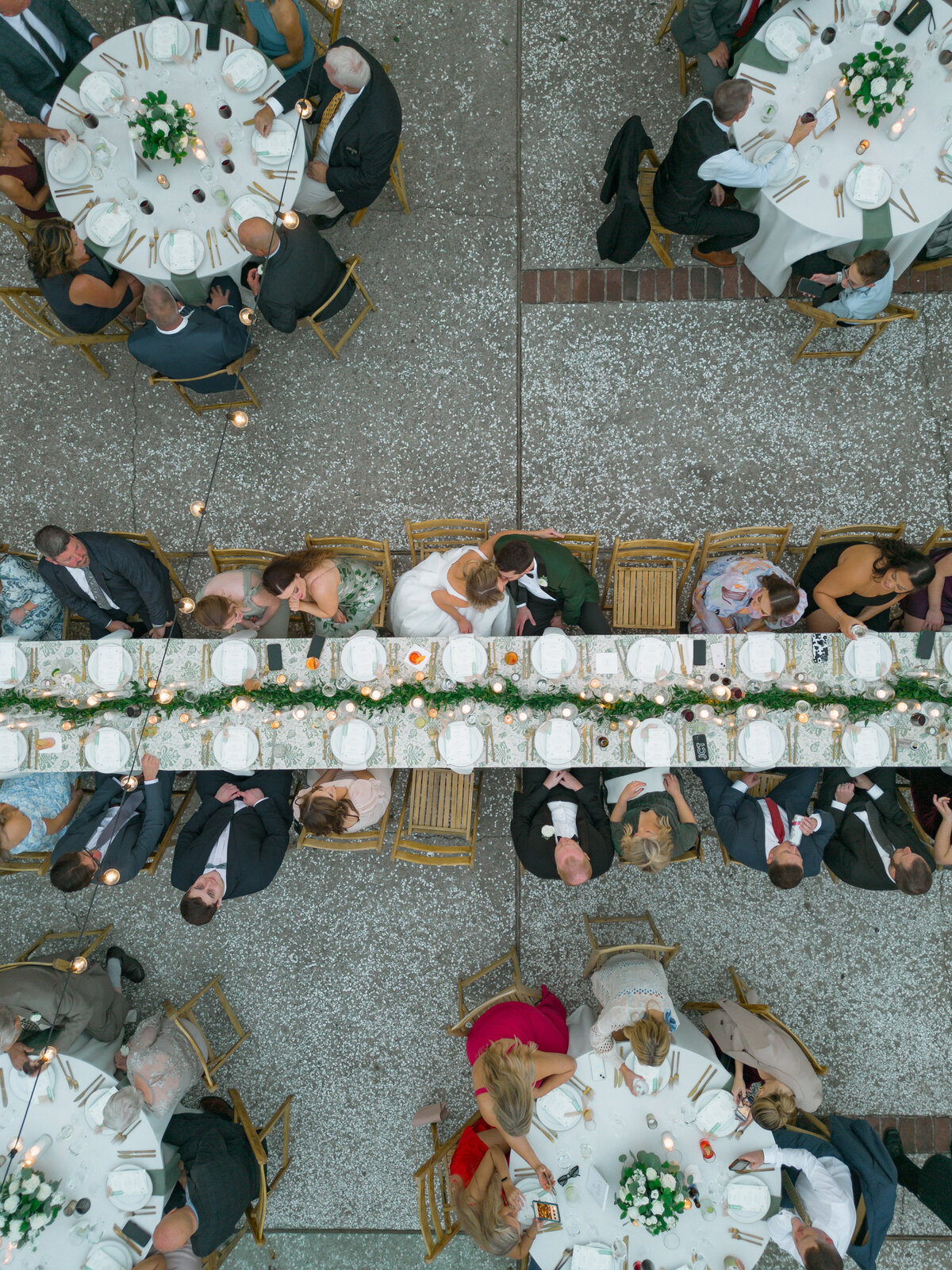 Charleston wedding photographer that has drone. Bride and groom kiss at the head table during open air wedding reception at William Aiken House.