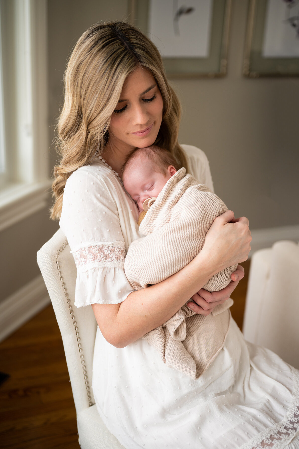 Mother holding her baby while wearing a white dress