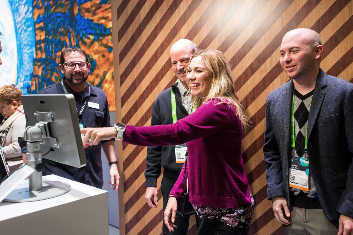 Group of four people look at screen on showroom floor at IAEE Expo