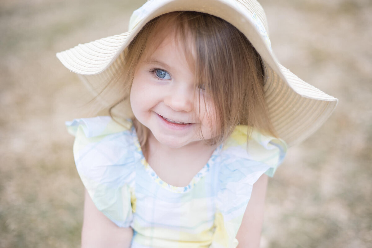 toddler girl in a sunhat with a big smile on her face looking to the left