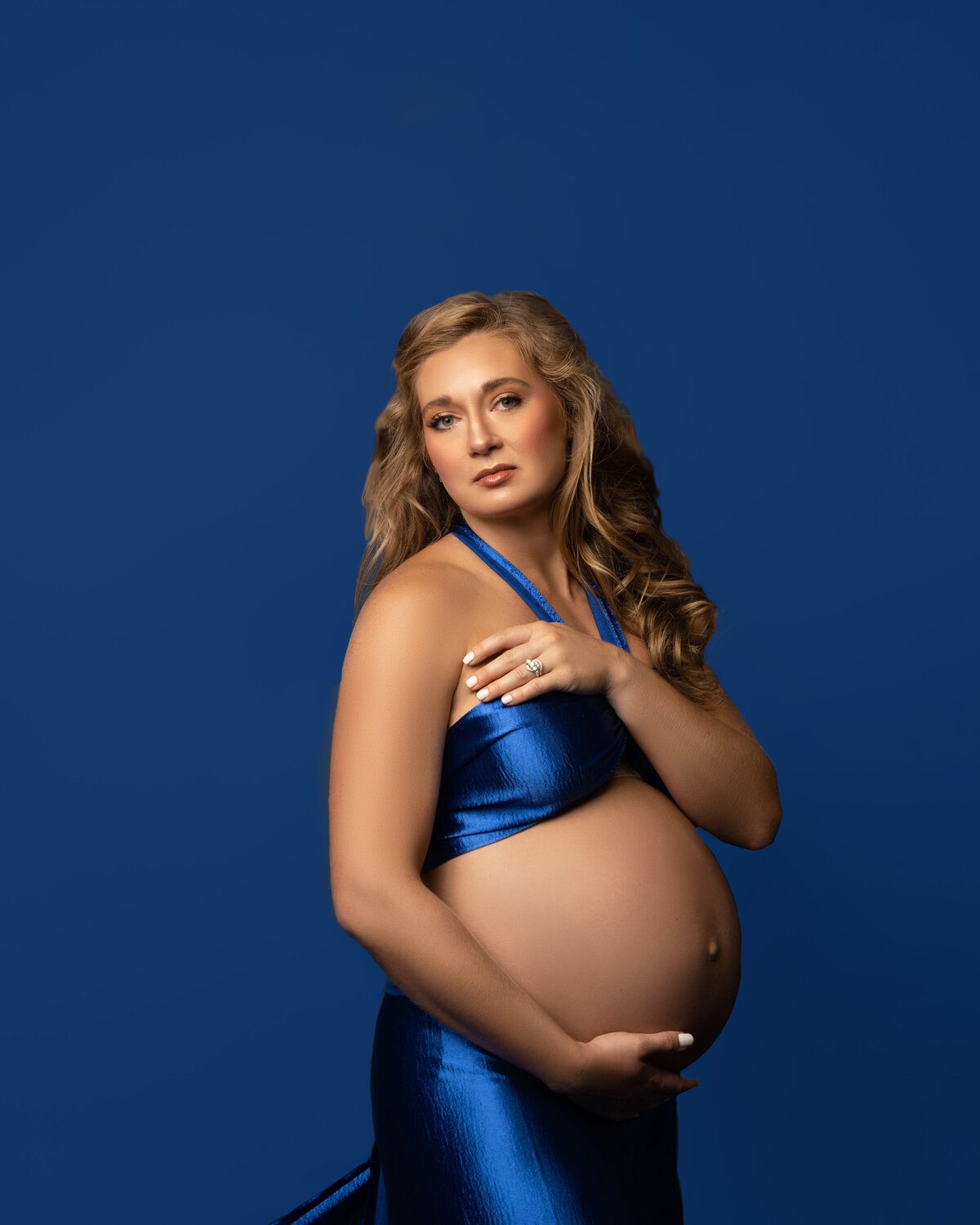 Woman exposed belly pregnant blond studio blue