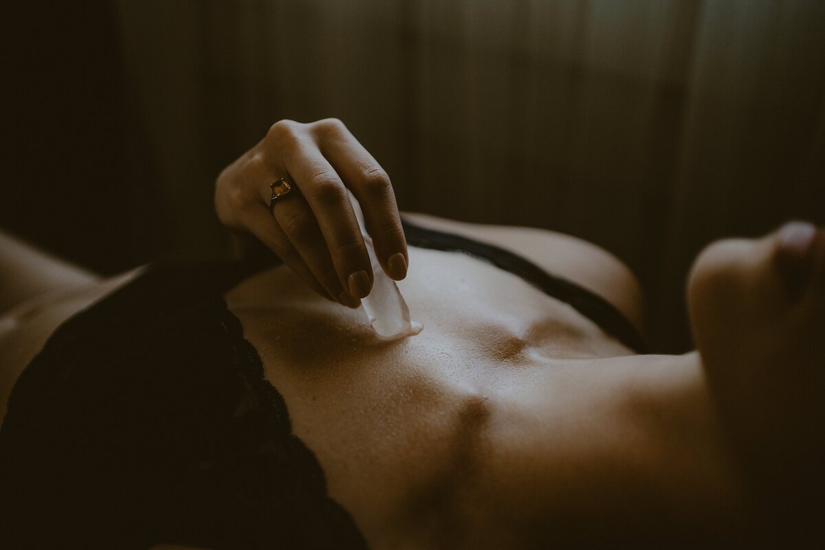 Black + White boudoir photo of woman arching her back in strappy lingerie