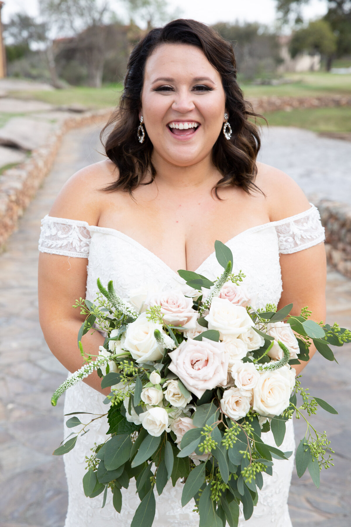n Austin wedding photographer captures the radiant smile of a bride as she delicately holds her beautiful wedding bouquet.