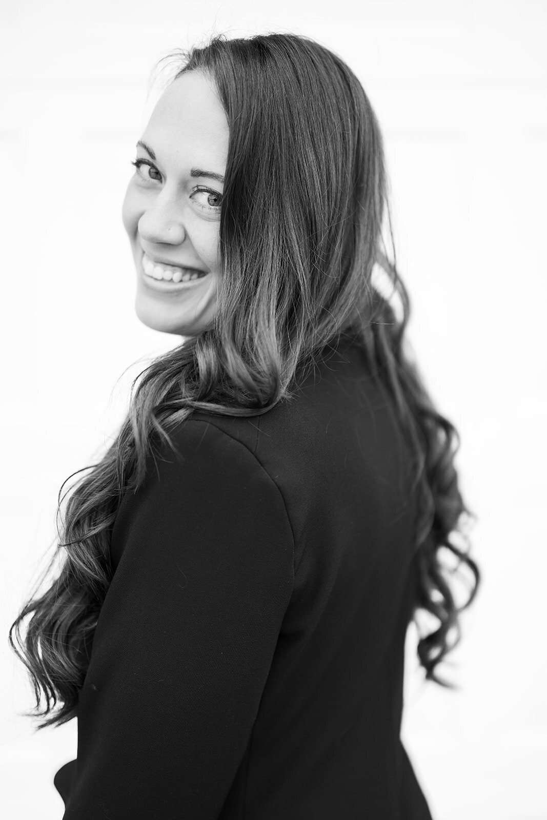 Black and white portrait of Amanda Briggs smiling over her shoulder