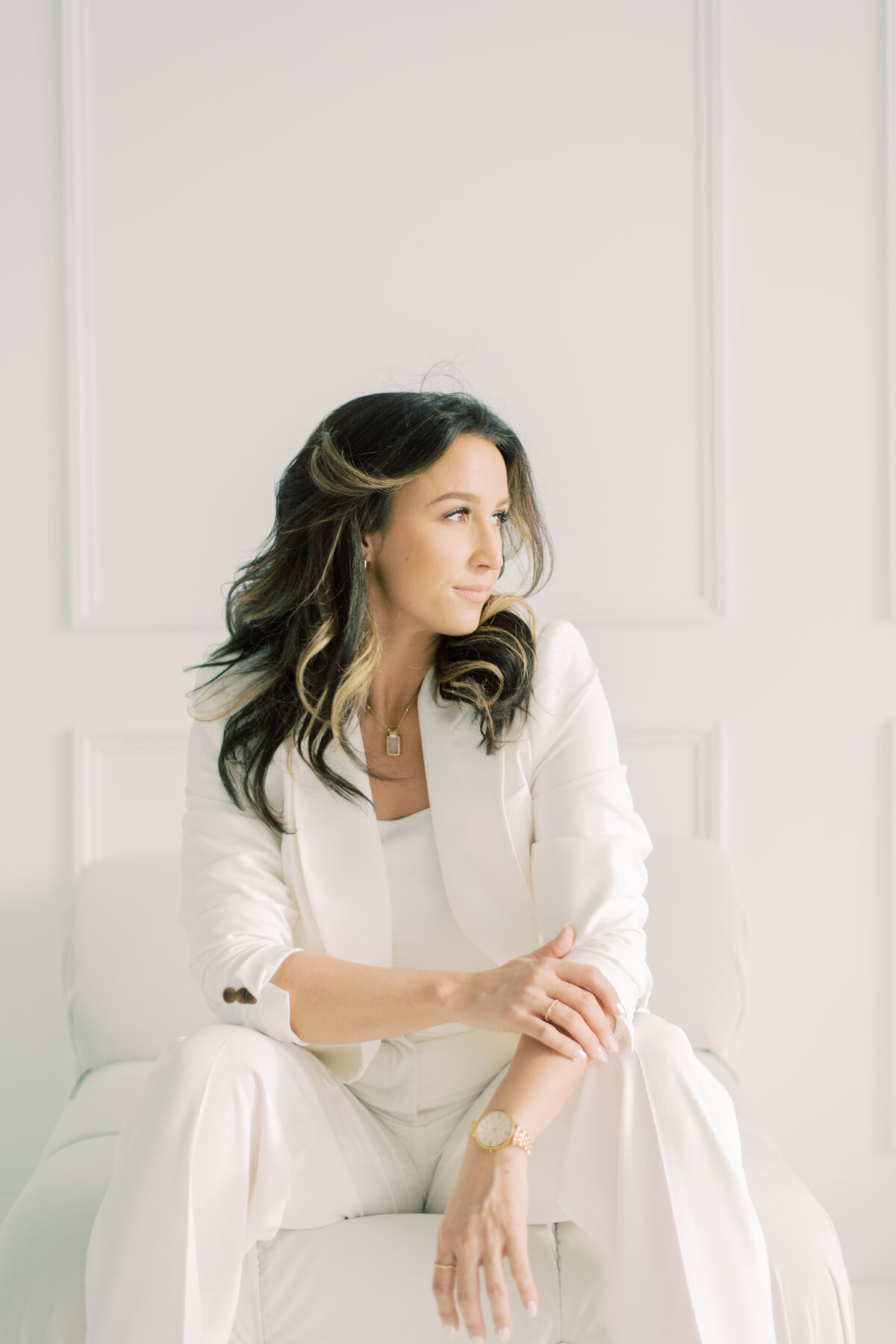 Poised branding headshot of woman seated in white jacket