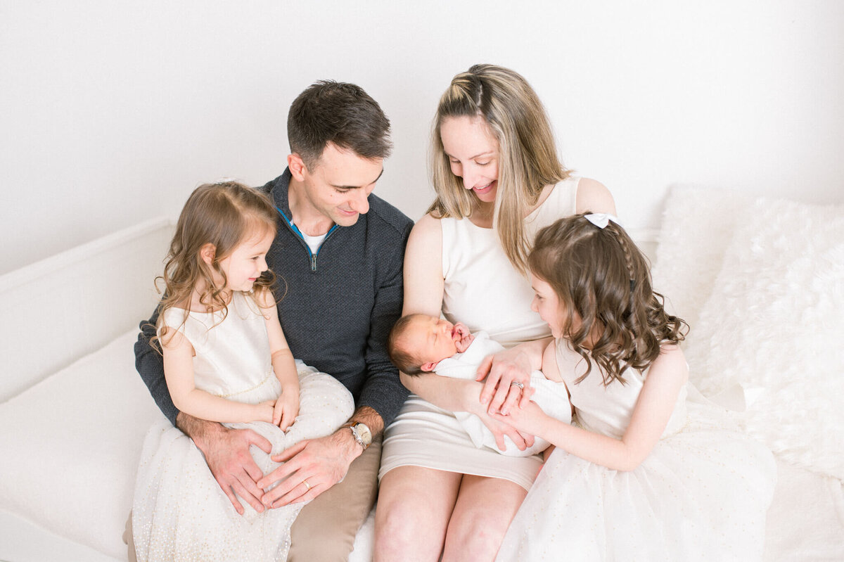 Beautiful family looking at newborn sister captured by Niagara newborn photographer in studio
