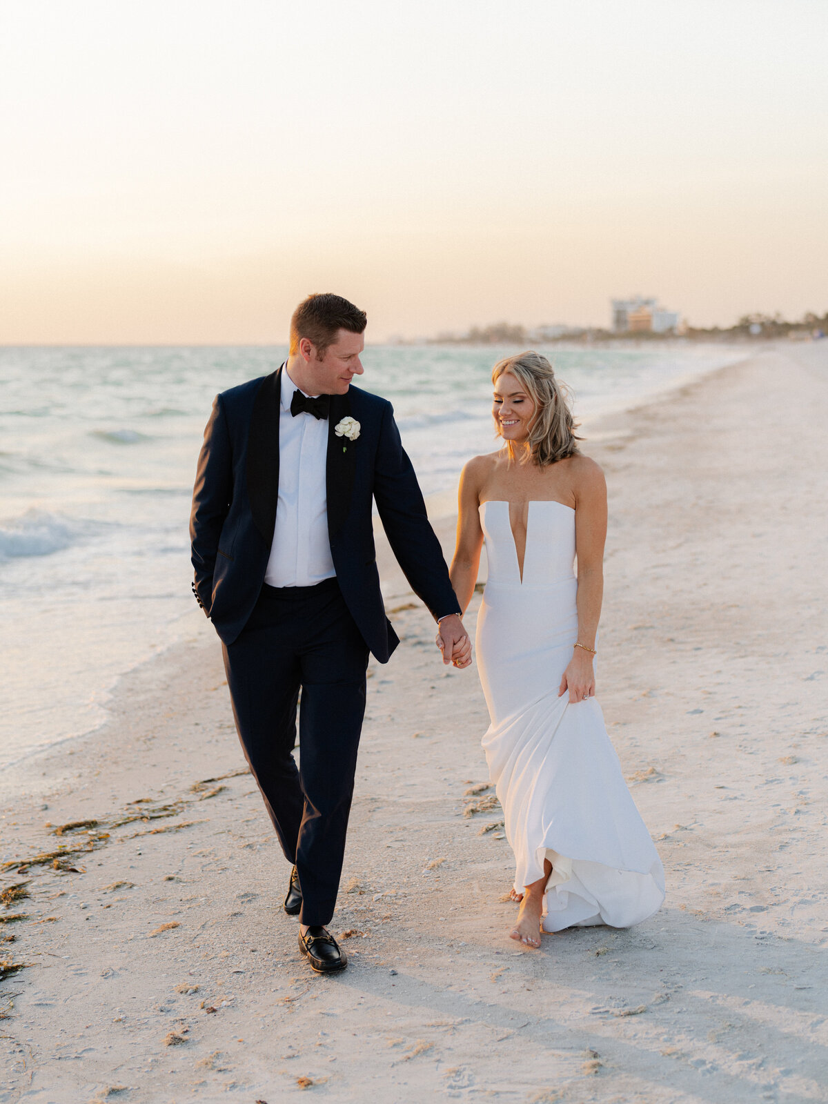 Bride and groom walking on sandy beach 