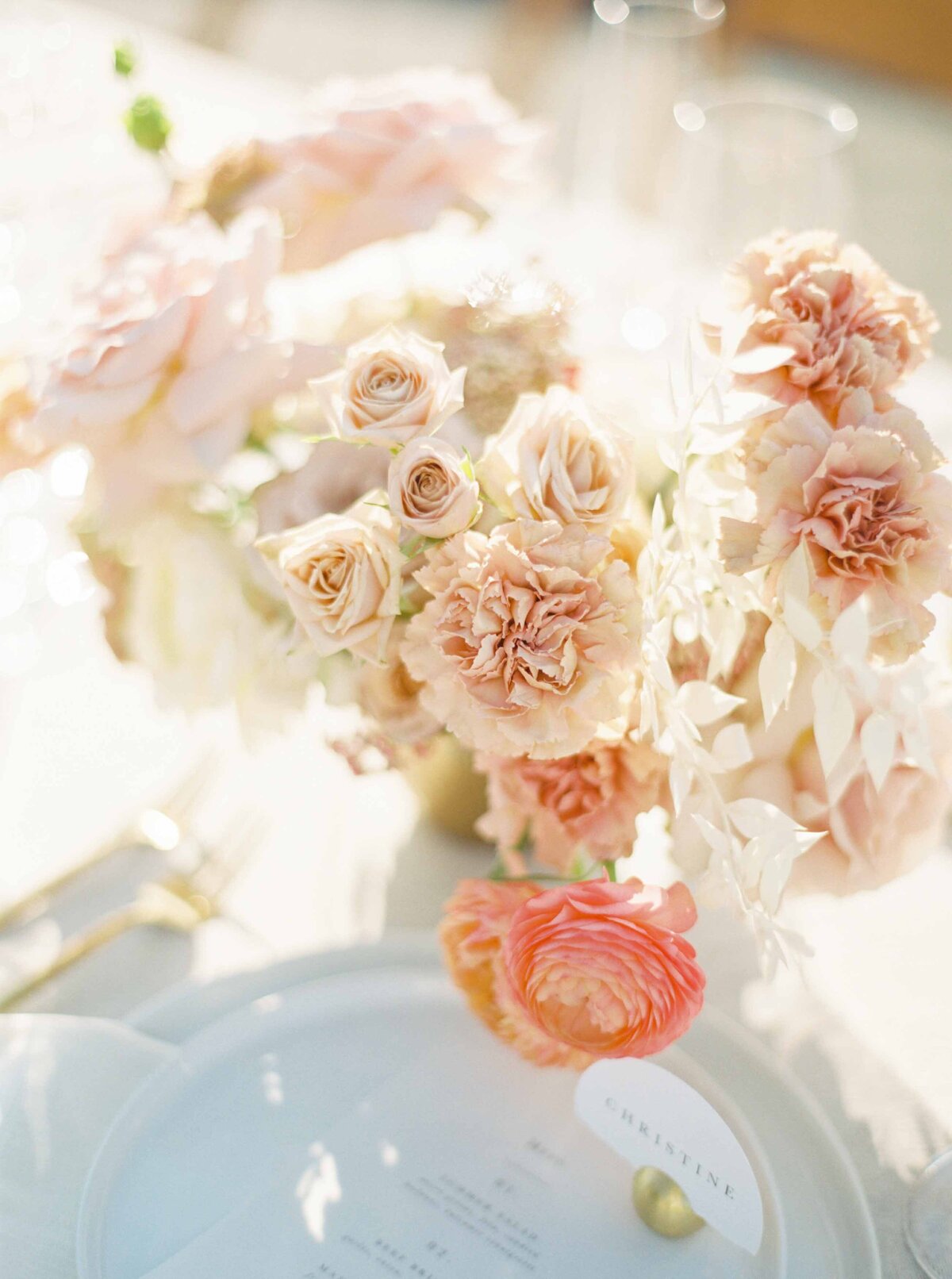 peach and blush soft floral centerpiece on an all white table at sunset