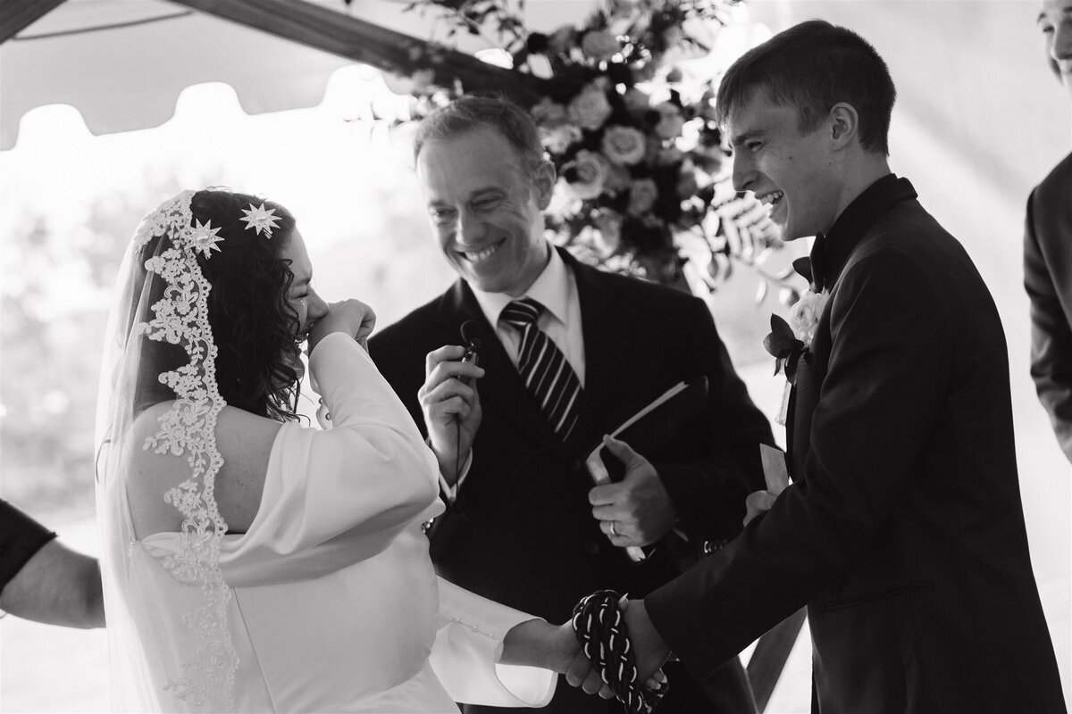 A bride and groom crying and laughing during their hand tying ceremony at their nashville wedding